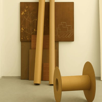 conceptual installation by artist Isaac Cohen exploring the poetics of engineering through minimalist industrial forms. Cardboard cylinders, a spool-like object, and etched panels with mechanical drawings muse on the creation of purpose by introducing design to simple materials. The work reflects on structure, function, and the transformation of raw components into objects imbued with meaning.